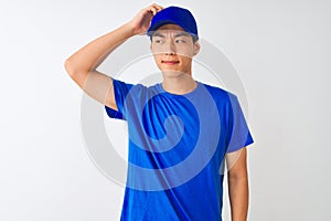 Chinese deliveryman wearing blue t-shirt and cap standing over isolated white background confuse and wonder about question