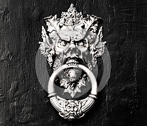 Chinese demon golden door handle - knocker in a black and white wooden door