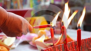 Chinese devotee lighting candles on a table