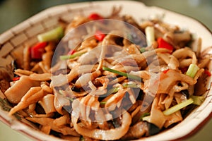 Chinese dish of meat, vegetables and chili peppers, served on a white plate. Beijing, China.