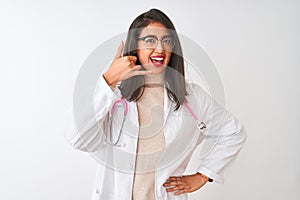 Chinese doctor woman wearing coat and pink stethoscope over isolated white background smiling doing phone gesture with hand and