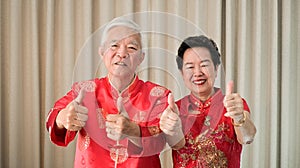 Chinese elderly senior couple in red costume thumb up gesture