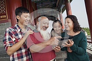 Chinese Family Looking At Digital Tablet In Jing Shan Park photo