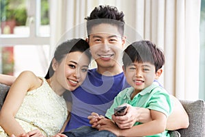 Chinese Family Watching TV On Sofa Together