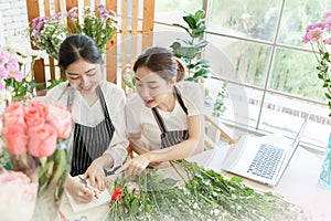 Chinese female florist writing order at flower shop