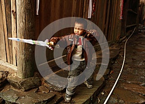 Chinese five year old boy playing with a plastic sword in the village street, editorial images.