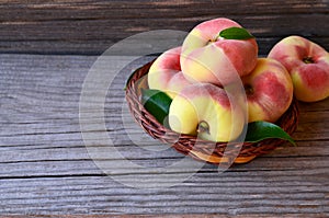 Chinese flat donut peaches in the basket on on old wooden table also known as Saturn donut, Doughnut peach, Paraguayo.Healthy eati photo