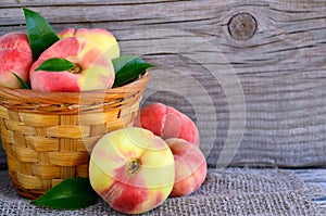 Chinese flat donut peaches in the basket on on old wooden table also known as Saturn donut, Doughnut peach, Paraguayo.Healthy eati photo