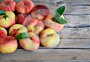 Chinese flat donut peaches with leaves on on old wooden table also known as Saturn donut, Doughnut peach, Paraguayo.Healthy eating photo