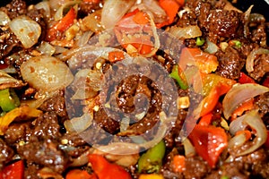 Chinese food cuisine of grilled beef red meat pieces and cubes with oil, mushroom, vegetables, peas, carrots, colorful peppers,