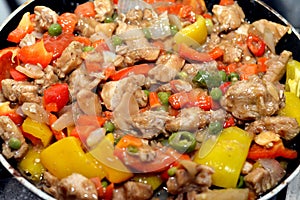 Chinese food cuisine of grilled chicken breast pieces and cubes with oil, mushroom, vegetables, peas, carrots, colorful peppers,
