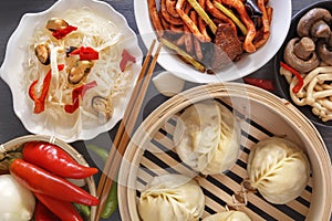 Chinese food on a gray wooden table. Traditional steam dumplings, noodles, vegetables, seafood.