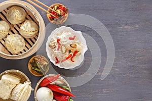 Chinese food on a gray wooden table. Traditional steam dumplings, noodles, vegetables, seafood.