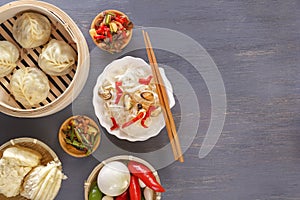 Chinese food on a gray wooden table. Traditional steam dumplings, noodles, vegetables, seafood.