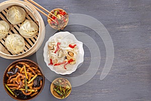 Chinese food on a gray wooden table. Traditional steam dumplings, noodles, vegetables, seafood