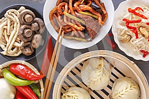 Chinese food on a gray wooden table. Traditional steam dumplings, noodles, vegetables, seafood.