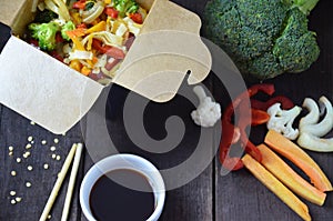 Chinese food, Noodles with pork and vegetables in take-out box on wooden table