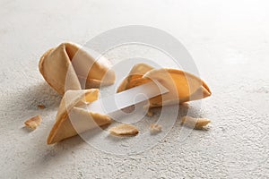 Chinese fortune cookies, one is cracked with blank paper slip for the prediction on a light background with copy space