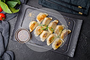 chinese fried dumplings dim sum with sauce on black stone board top view