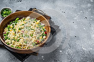 Chinese Fried rice with egg and vegetables in a wooden plate. Gray background. Top view. Copy space