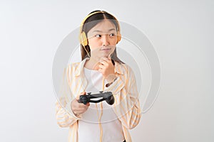Chinese gamer woman playing video game using headphones over isolated white background serious face thinking about question, very
