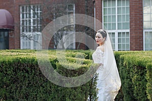 Chinese Girl bride in wedding dress with a beautiful imperial crown stand in the bushes