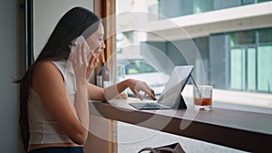 Chinese girl making call choosing purchases on laptop at coffeeshop close up.