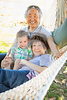 Chinese Grandparents In Hammock with Mixed Race Grandchild