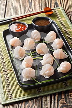 Chinese Har Gow Dim Sum dumplings in the shape of a bonnet served with sauce. Vertical
