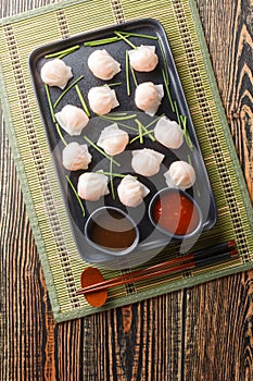 Chinese Har Gow Dim Sum dumplings in the shape of a bonnet served with sauce. Vertical top view