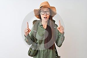 Chinese hiker woman wearing canteen hat glasses backpack over isolated white background amazed and surprised looking up and