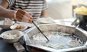 Chinese hot pot with beef and table with lots of delicious ingredients