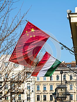 Chinese and Hungarian flags on a background of blue sky and city houses