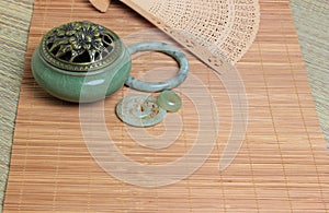 Chinese incense burner, traditional nephrite jewelry and on the bamboo mat background. still-life. copy space