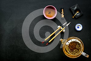 Chinese or japanese traditions. Calligraphy and tea ceremony concept. Special writting pen, ink near teapot and cup of