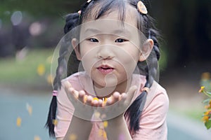 Chinese kid blowing petal to fly in hands