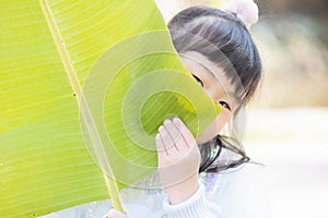 Chinese kid cover face with banana leaf making fun