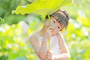 Chinese kid holding stem of lotus leaf above head