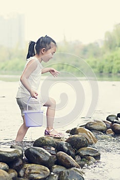 Chinese kid play in river with bucket