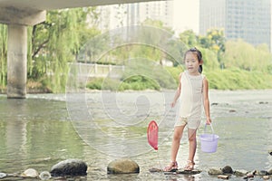Chinese kid play in river with butterfly net and bucket