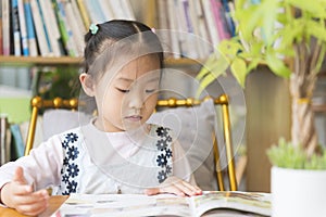 Chinese kid reading picture book in library