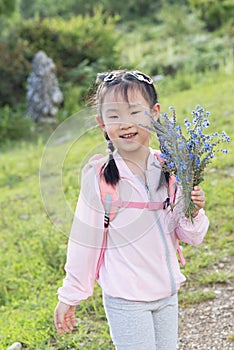 Chinese kid taking a happy day in field, bunch of wildflowers in hand