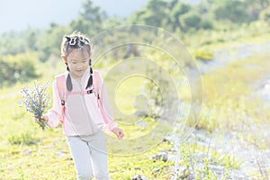 Chinese kid taking a happy day in field, bunch of wildflowers in hand