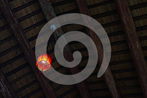 Chinese lamp hanging from a wooden ceiling