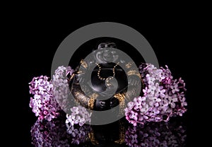 Chinese laughing buddha Hotei or Budai framed by pink lilac flowers on a black background photo