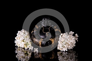 Chinese laughing buddha Hotei or Budai framed by white lilac flowers on a black background photo