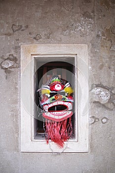 Chinese lion mask in the cement window wall.