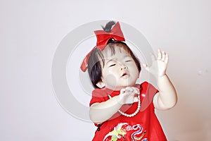 Chinese little baby in red cheongsam scared by soap bubbles