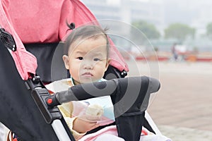 Little daughter in baby carseat with bun in hand photo