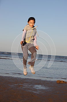 Chinese little girl jumping on the beach